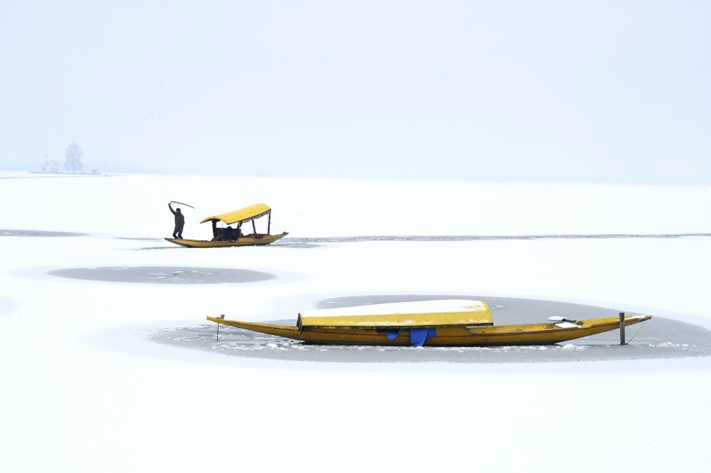 Un barquero dirige su bote en el lago Dal parcialmente congelado después de una nevada en Srinagar.