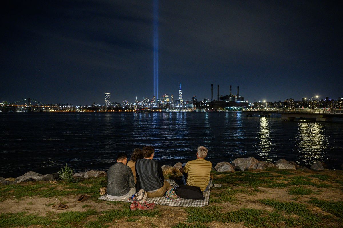 Personas están sentadas frente al río este y observan la instalación Tribute in Light en medio del horizonte de la ciudad de Manhattan que conmemora los ataques terroristas del 11 de septiembre, en Nueva York el 10 de septiembre de 2022. Foto: AFP