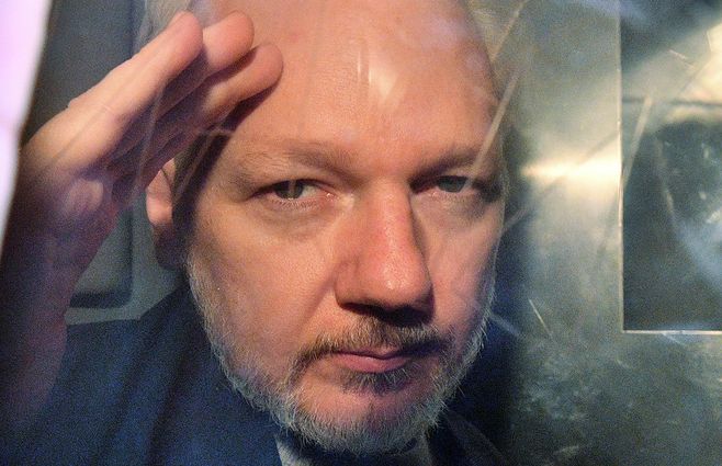 Assange hace gestos desde la ventana de una camioneta después de haber sido condenado a prisión.