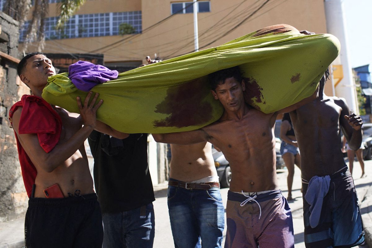 Residentes de la favela Complexo do Alemao cargan el cadáver de un hombre muerto durante una redada policial en Río de Janeiro, Brasil, el 21 de julio de 2022. Foto: AFP