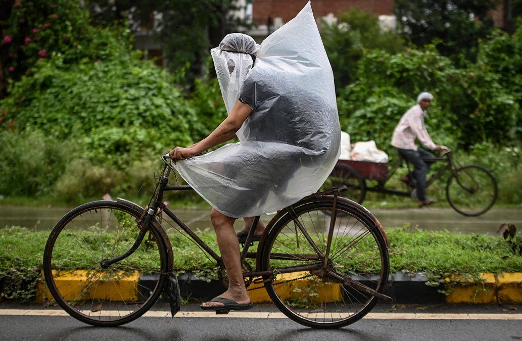 Unciclista se cubre con un plástico durante un aguacero en Faridabad,India.