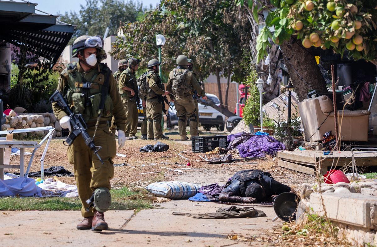 Los soldados israelíes están cerca del cuerpo de un militante palestino en Kfar Aza, al sur de Israel, cerca de la Franja de Gaza, el 10 de octubre de 2023.