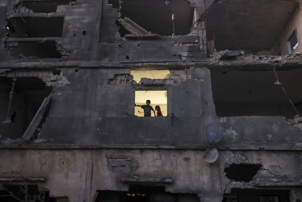 Los niños palestinos se paran en la ventana de su casa en un edificio gravemente dañado durante los recientes ataques israelíes