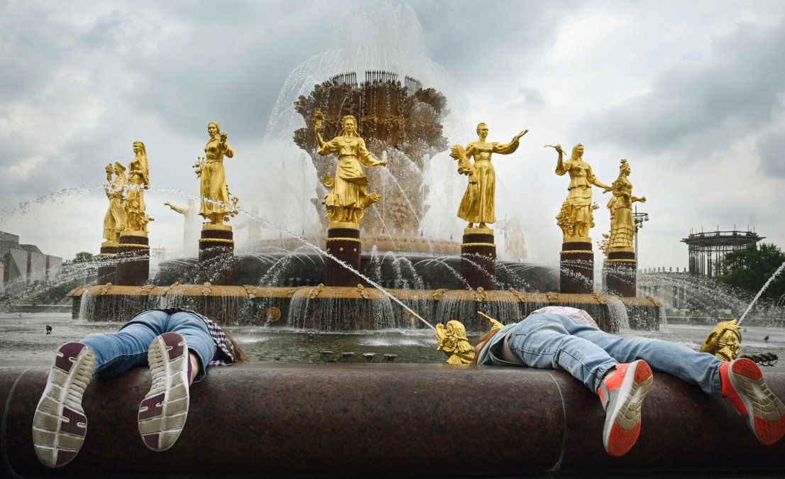 Los niños intentan sacar monedas de la fuente Amistad de las Naciones, construida en 1954, que simboliza la amistad de dieciséis repúblicas soviéticas que forman la URSS, en el Centro de Exposiciones de toda Rusia