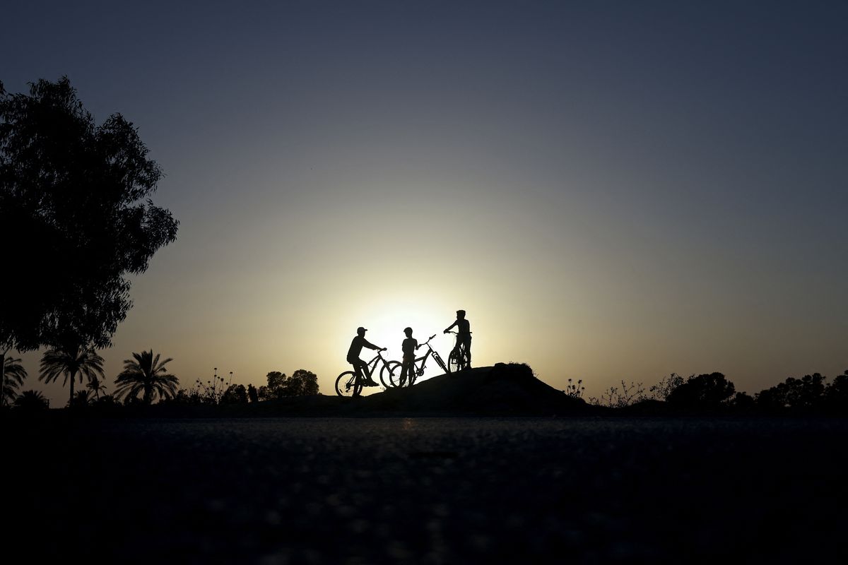 Niños palestinos andan en bicicleta durante la puesta de sol en la ciudad de Gaza, el 9 de junio de 2022.