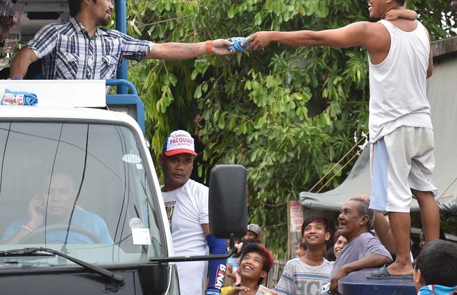 Manny entrega una remera a un militante en la campaña que lo llevó al senado en el 2016