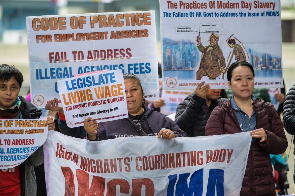 Empleadas domésticas migrantes y activistas sostienen pancartas mientras participan de la protesta en reclamo por mejores condiciones de trabajo para marcar el #8M.