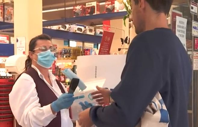 Un cliente recibe un tapabocas antes de entrar al comercio durante la reapertura del centro. Archivo