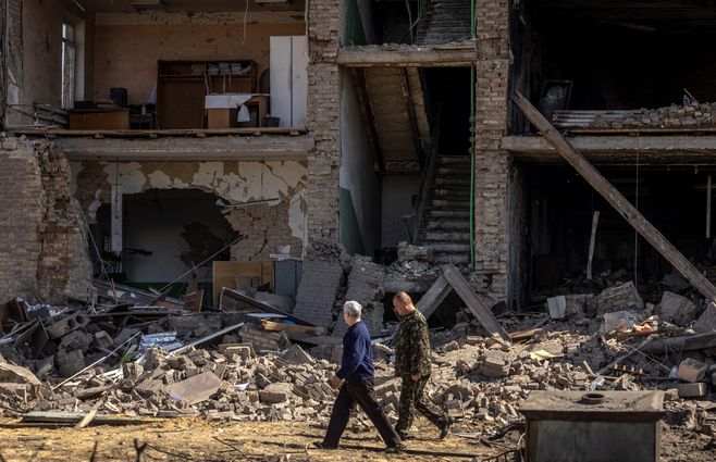 Personas caminan frente a un edificio bombardeado en Ucrania abril 2022 AFP.jpg