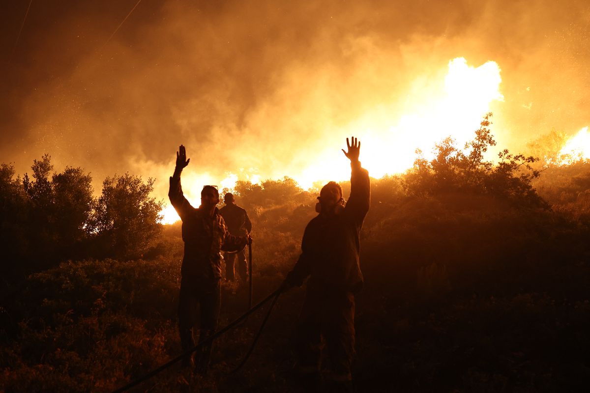 Los bomberos hacen un gesto mientras trabajan para extinguir un incendio forestal&nbsp; al norte de Atenas, el 19 de julio de 2022. Foto: AFP