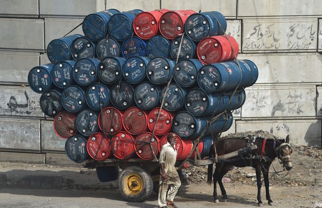 Un carro tirado por un caballo, cargado de bidones de aceite en una calle de Lahore, Pakistán.
