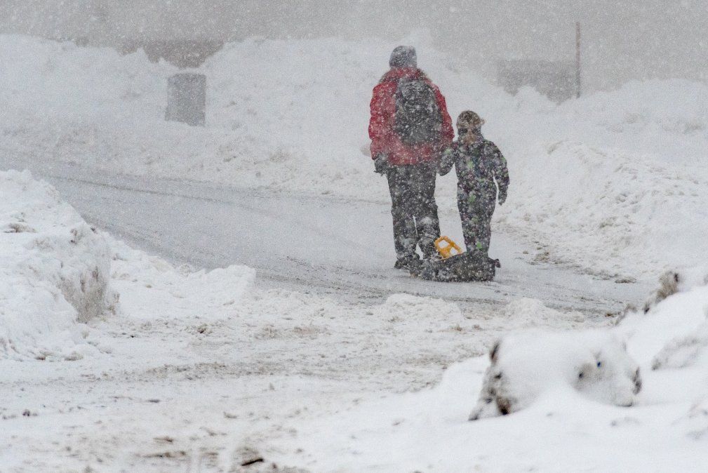 Una mujer y un niño caminan con un trineo a lo largo de una calle repleta de nieve en Sankt Englmar, Alemania.