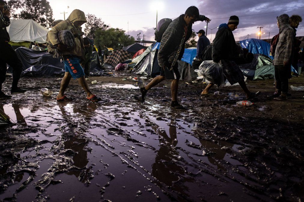 Migrantes centroamericanos acarrean sus pertenencias tras una fuerte lluvia en un refugio temporal en Tijuana.